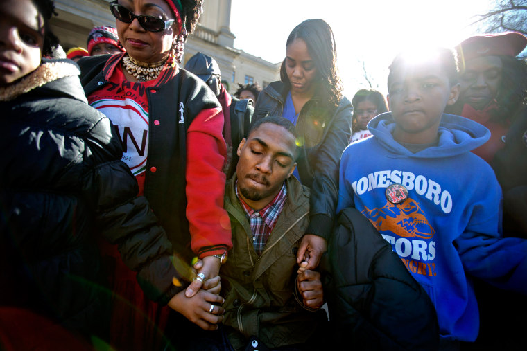 Leon Ford, center, joins hands with supporters during a rally in memory of Kendrick Johnson, the Georgia teenager found dead inside a rolled-up wrestling mat in his school, Dec. 11, 2013, in Atlanta.