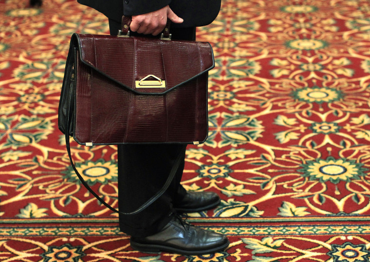 A man holds his briefcase while waiting in line during a job fair in Melville, New York July 19, 2012.
