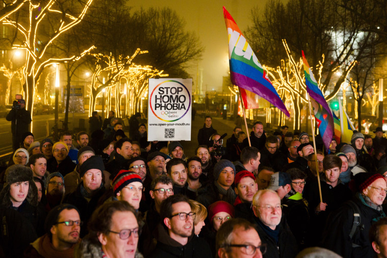 People hold a placard and rainbow flags as they call on the Russian authorities to lift anti-gay laws ahead of the Sochi 2014 Olympics during a protest outside the Russian embassy in Berlin, Dec. 12, 2013.