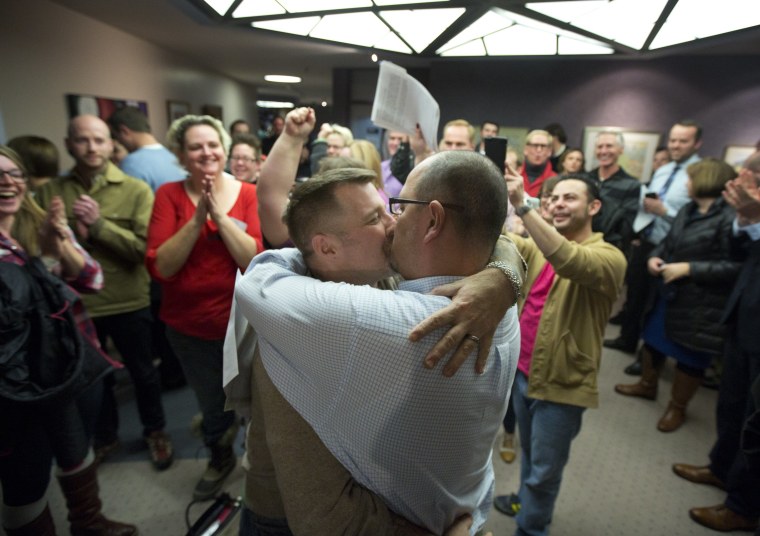 Chris Serrano, left, and Clifton Webb kiss after being married, as people wait in line to get licenses outside of the marriage division of the Salt Lake County Clerk's Office in Salt Lake City, Friday, Dec. 20, 2013.