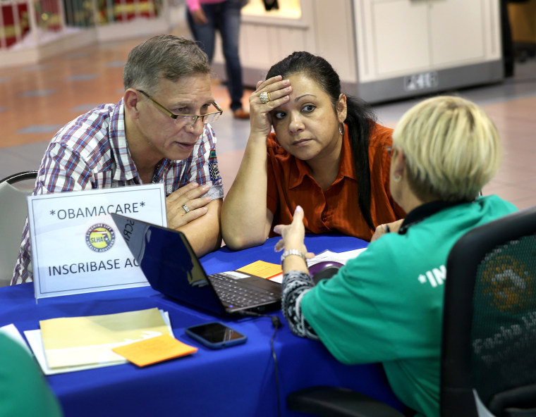 Angel Rivera (L) and his wife Wilma Rivera sit with, Amada cantera, an insurance agent with Sunshine Life and Health Advisors as they try to purchase health insurance under the Affordable Care Act at the kiosk setup at the Mall of Americas, Dec. 22, 2013