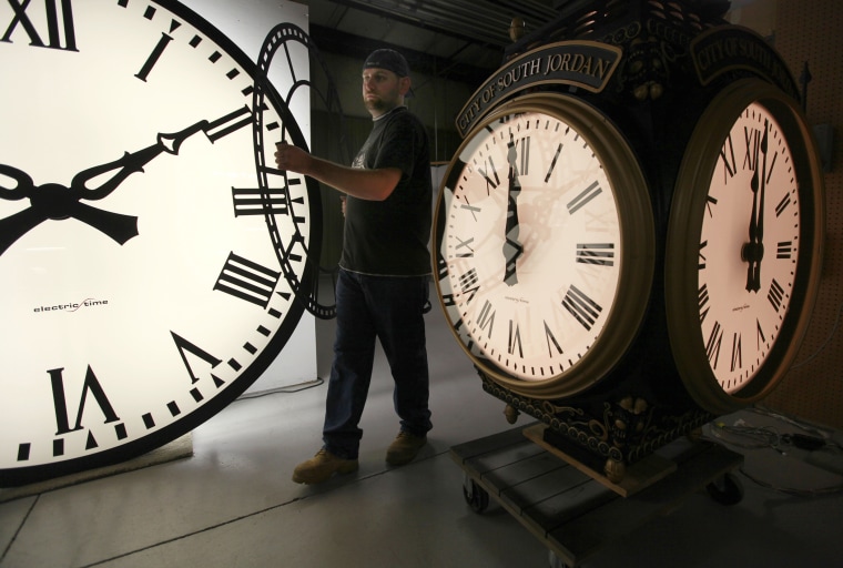 In this Thursday, Nov. 3, 2011 photo, Dan LaMoore of Electric Time Company moves a clock face at their plant in Medfield, Mass.