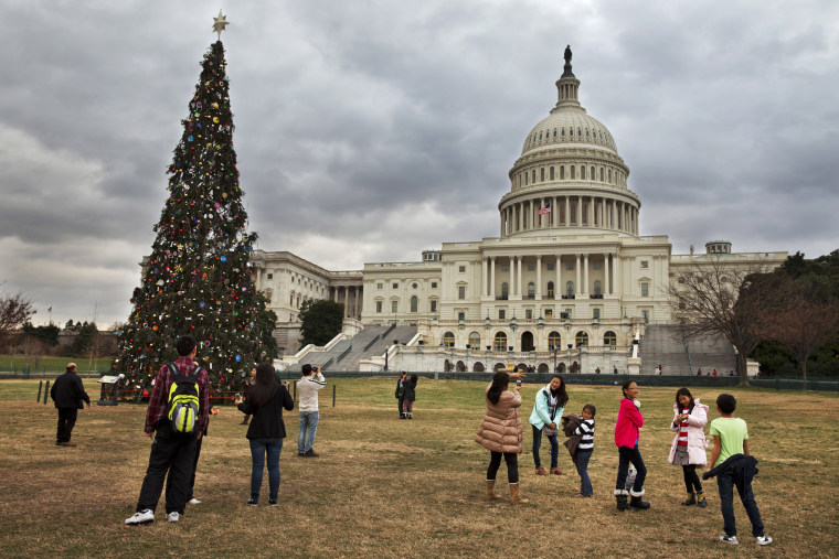 Under rolling clouds, tourists remove their jackets as they visit the U.S. Capitol Christmas tree in Washington, Sunday, Dec. 22, 2013.