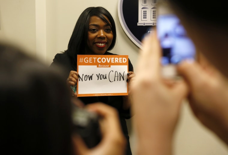 A woman poses for photos while holding a placard with her thoughts on healthcare at the White House, Dec. 4, 2013.