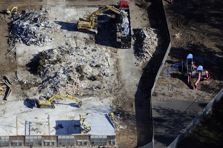 Workers use backhoes to dig through the rubble as the demolition of Sandy Hook Elementary School continues, Oct. 28, 2013.