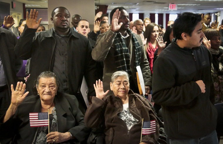 Immigrants raise their hands to become new citizens during the Oath of Allegiance at a naturalization ceremony on Wednesday, Dec. 18, 2013 in New York.