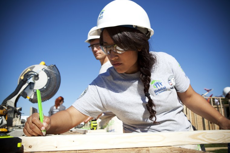 AmeriCorps volunteer Victoria Piar from Habitat for Humanity of Orange County, saws lumber for a new house frame.