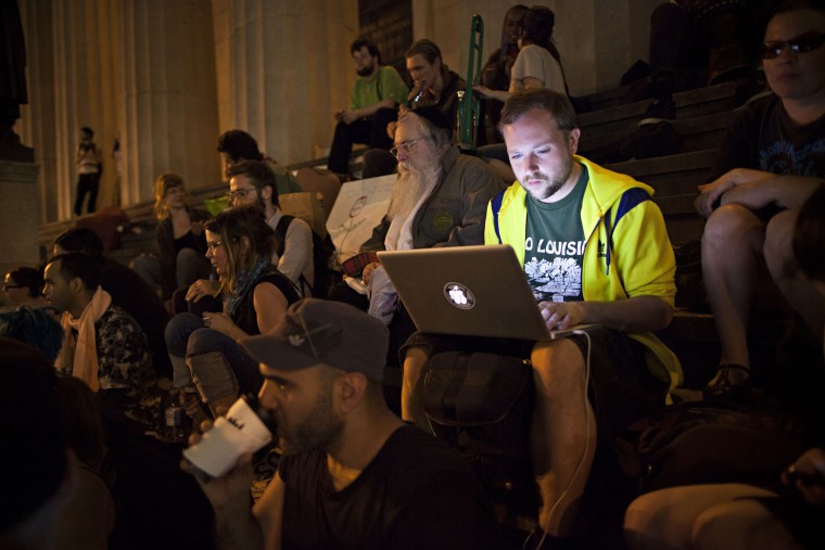 An Occupy Wall Street protester works on a laptop on the steps of Federal Hall