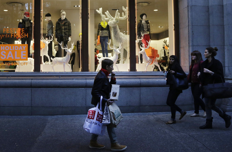 In this Friday, Nov. 22, 2013 photo, shoppers walk past windows at a Joe Fresh clothing store in New York.