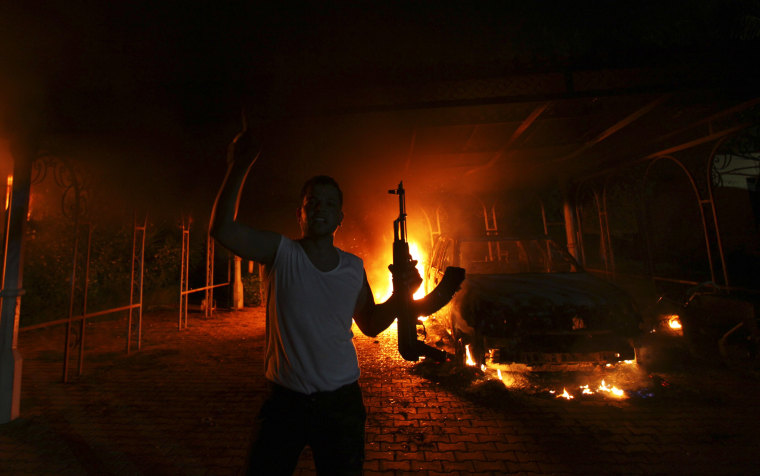 A protester reacts as the U.S. Consulate in Benghazi is seen in flames during a protest by an armed group said to have been protesting a film being produced in the United States September 11, 2012.