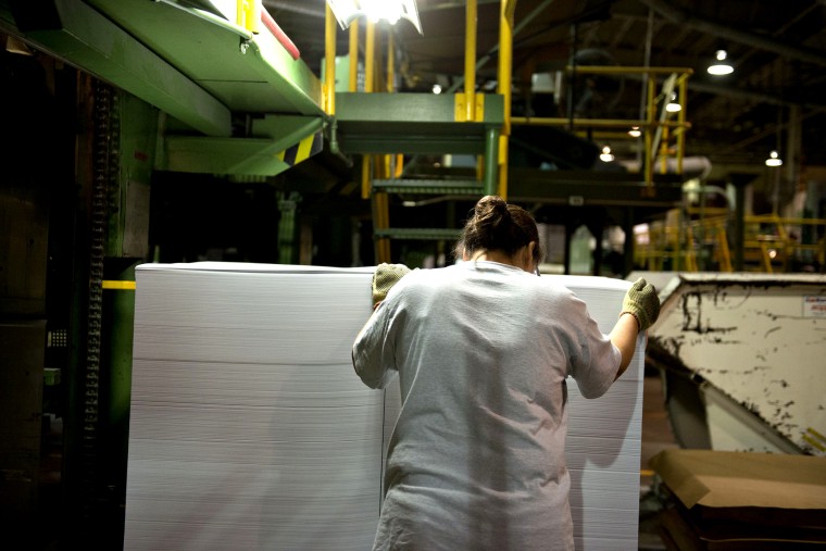 An employee guides a stack of cut paper as it is unloaded from a cutting machine at a paper mill in Rothschild, Wisconsin, U.S., on Wednesday, Oct. 10, 2012.