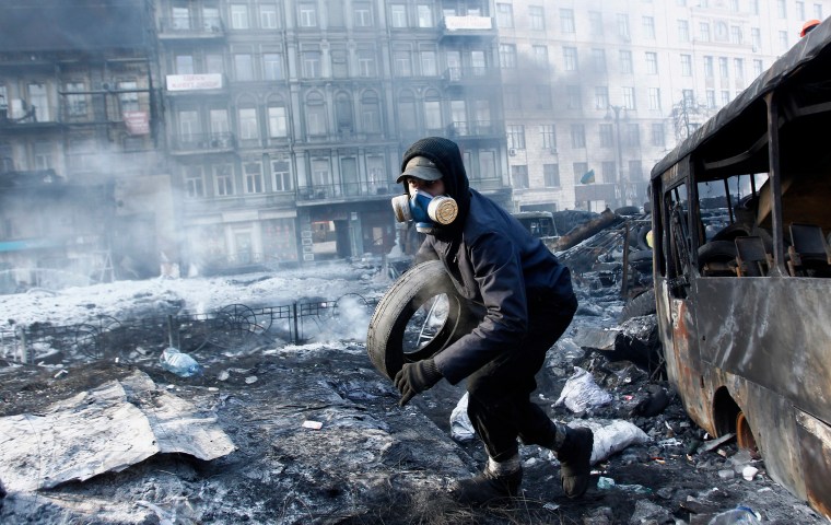 An anti-government protester carries a tire at the site of clashes with riot police in Kiev on Jan. 26, 2014.