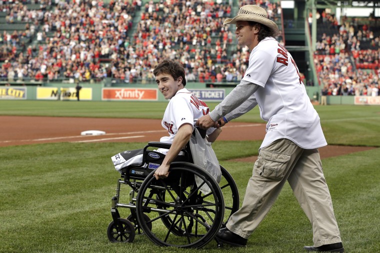 Boston Marathon bombing survivor Jeff Bauman, left, is wheeled out by Carlos Arredondo, the man who helped save his life, to throw out the ceremonial first pitch at Fenway Park, May 28, 2013.