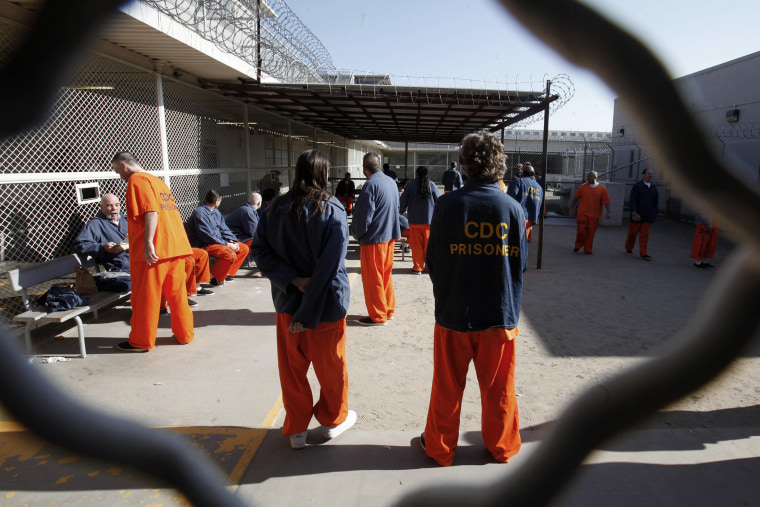 Inmates walk around a recreation yard at the Deuel Vocational Institution in Tracy, Calif.
