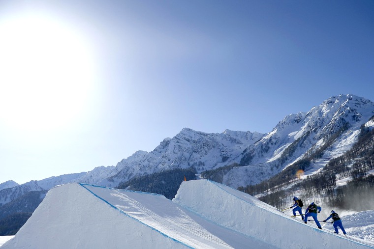 Officials prepare a jump on the slopestyle snowboard course during a break in practice for the 2014 Sochi Winter Olympics in Rosa Khutor Feb. 4, 2014.