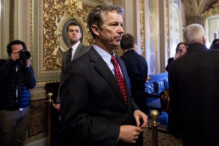 Rand Paul talks with a staff member as he walks to participate in a cloture vote at the US Capitol. Feb. 12, 2014.