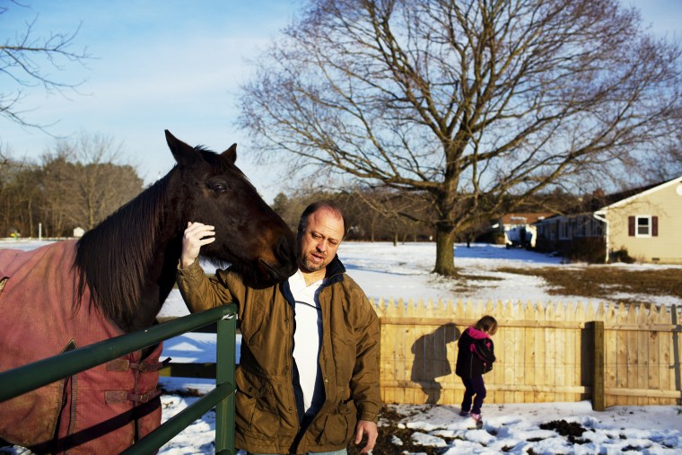 Paul Moody pets one of his horses in the front yard of his home, where he lives with his wife and four daughters and numerous pets, including 6 horses, 5 dogs, and 3 cats in Ridgely, Maryland.