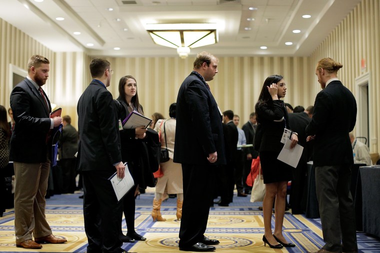 Attendees wait in line to speak with a prospective employer at a job fair on March 8, 2014.