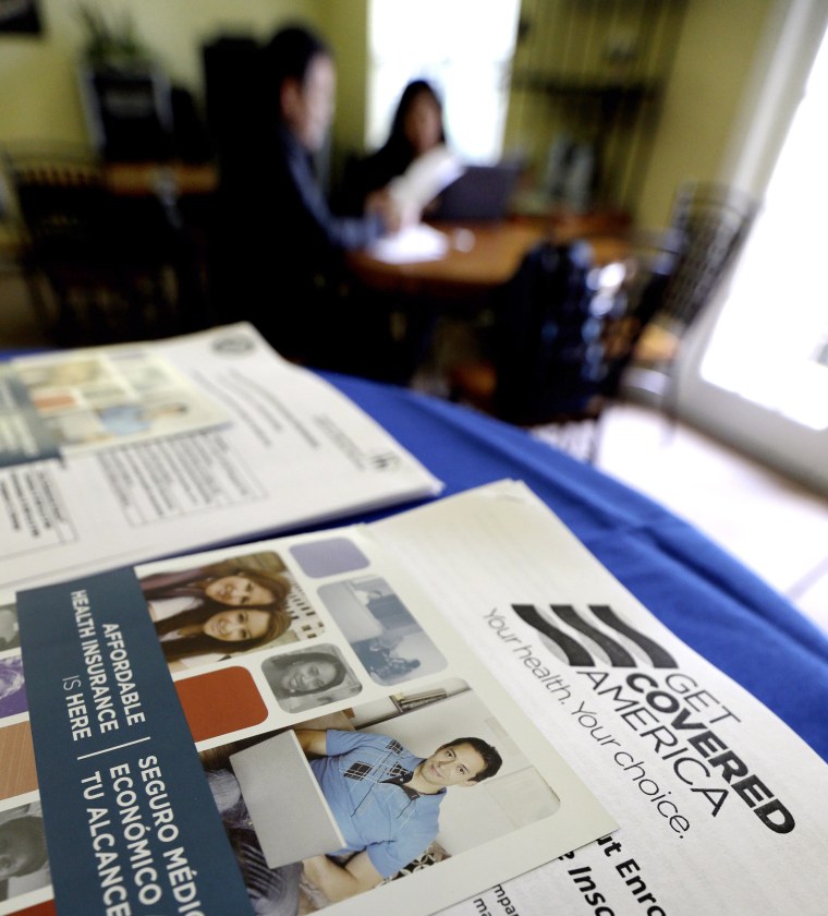 In this March 10, 2014 photo, with Health care information in the foreground, participants learn more about their health care options.