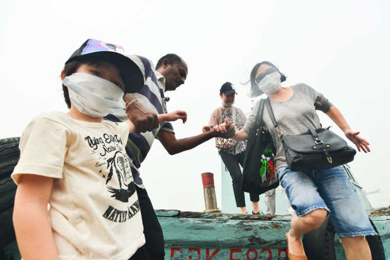 Tourists with masks get off a boat in Port Klang, Malaysia, March 14, 2014.