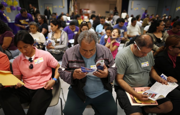Jesus Dominguez (C), 63, who does not have health insurance, reads a pamphlet at a health insurance enrollment event in Cudahy, California March 27, 2014.