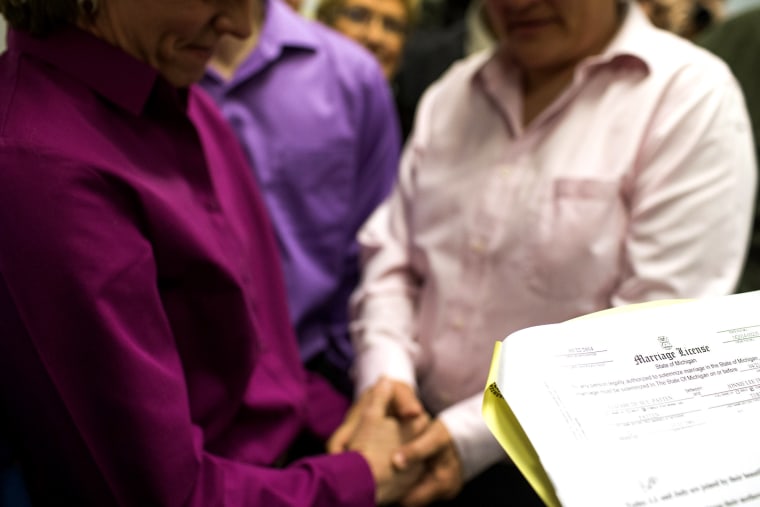 A gay couple holds hands during their marriage ceremony at the Washtenaw County Clerk's Office in Ann Arbor, Mich., on March 22, 2014.