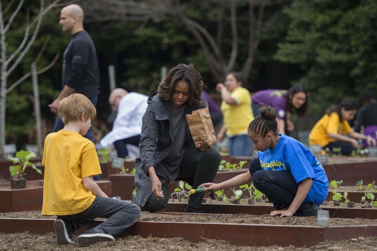US First Lady Michelle Obama plants with students from Friendship Public Charter Elementary in the White House Kitchen Garden at the White House in Washington, DC, on April 2, 2014.