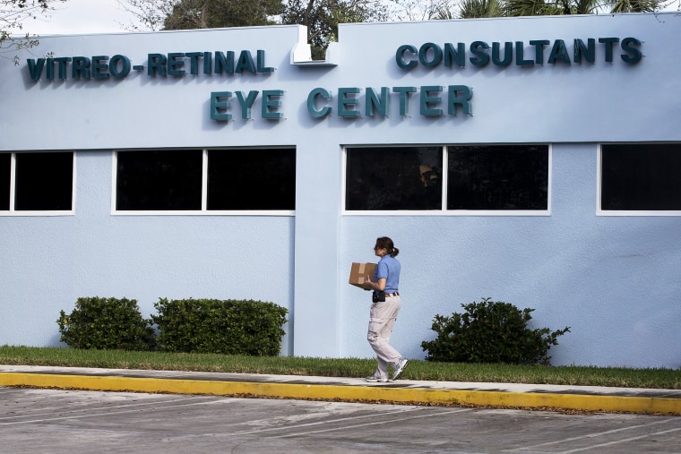 A woman carries a box of equipment into the Vitreo-Rential Consultants Eye Center in West Pam Beach, Fla., Jan. 30 2013.