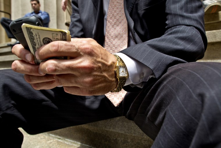 A businessman holding a cellphone and money in downtown Manhattan.