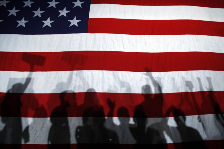 Supporters cast shadows on a U.S. flag as they cheer during a campaign rally.