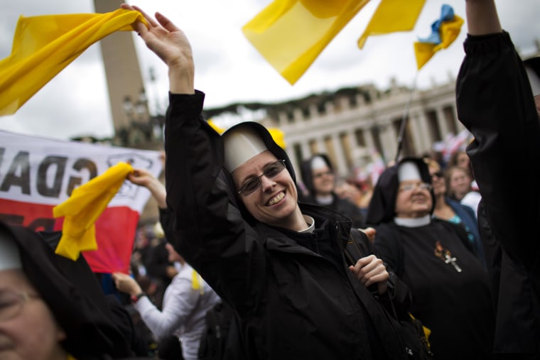 Nuns wave as Pope Francis is driven through the crowd after presiding over a solemn ceremony in St. Peter's Square at the Vatican, Sunday, April 27, 2014.