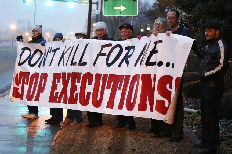 Death penalty opponents hold a sign outside the Governor's mansion in Oklahoma City, Jan. 9, 2014.