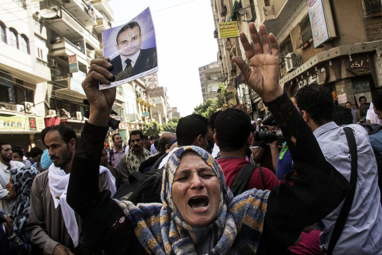 An Egyptian woman holds a photo of her son after a judge sentenced to death 683 alleged supporters of the country's ousted Islamist president in the latest mass trial in the southern city of Minya, Egypt, April 28, 2014.