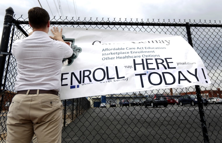 Ryan Witt hangs a sign outside offering assistance signing up for health insurance in St. Louis, March 31, 2014.