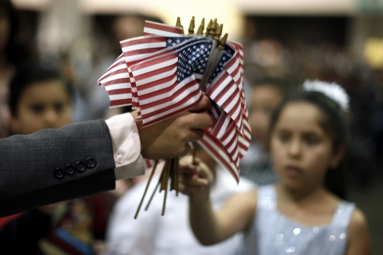 A man hands out U.S. flags at a naturalization ceremony for new U.S. citizens in Los Angeles