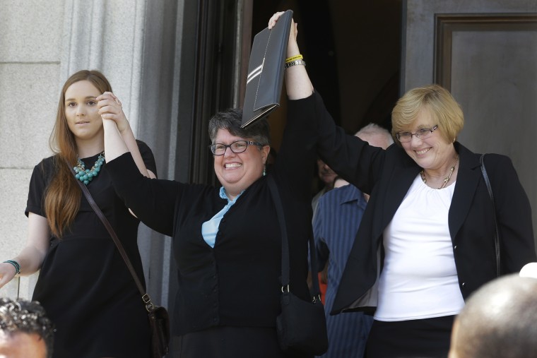 Plantiffs in the federal suit over Virginia's ban on gay marriage, Emily Schall-Townley, left, Carol Schall, center, and Mary Townley, raise their arms after a hearing on Virginia's same sex-marriage ban in Richmond, Va., on May 13, 2014.