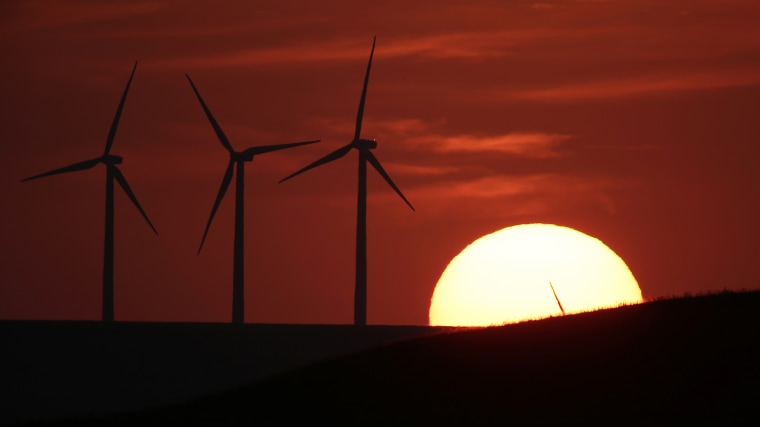 Wind turbines are silhouetted by the setting sun on Aug. 23, 2013, near Beaumont, Kan.