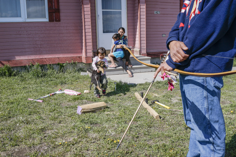 Joe Giago (holding bow) with his family at their home in Pine Ridge.  Joe makes traditional bows for locals and national and international collectors.  He is self-taught, and it took him over a year of study to perfect the technique.  The bows are made from Ash wood, buffalo horn, and the sinews of buffaloes, with horse hair for adornment.