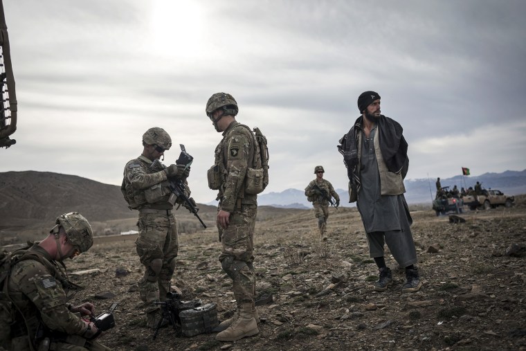 Soldiers from the 101st Airborne Division stand next to an Afghan suspected of Taliban connections in Lakaray, Afghanistan, April 14, 2013.
