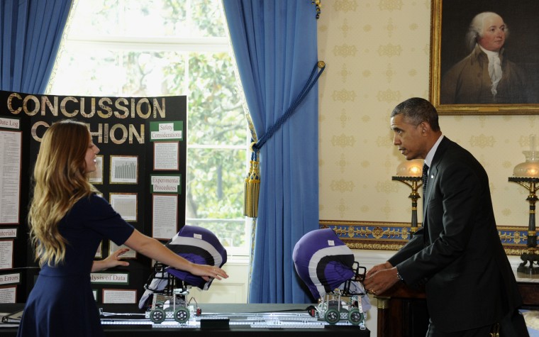 Maria Hanes, 19, of Santa Cruz, Calif., left, has President Barack Obama pull back a cushioned helmet as Obama toured the 2014 White House Science Fair exhibits that are on display in the State Dining Room of the White House in Washington, May 27, 2014.