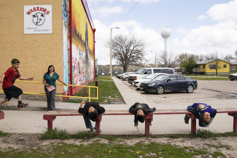 Alice Phelps watches students as they play while waiting for the bus on the last day of school at the Wounded Knee District School in Manderson.