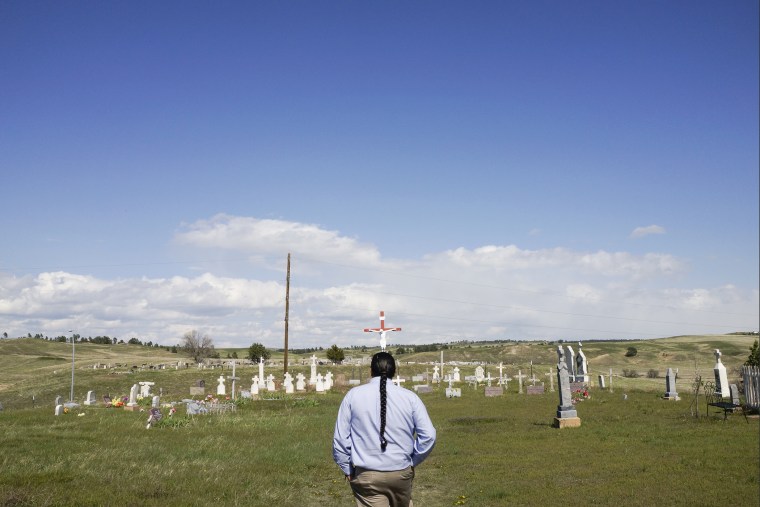 Community Relations coordinator Oitancan Zephier walks through the cemetery above the Red Cloud school in Pine Ridge.