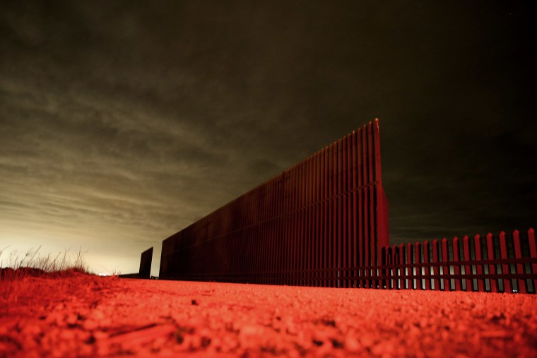 Lit by the tail light of a U.S. Border Patrol vehicle, a section of the U.S.- Mexico border fence stands on April 10, 2013 in La Joya, Texas.