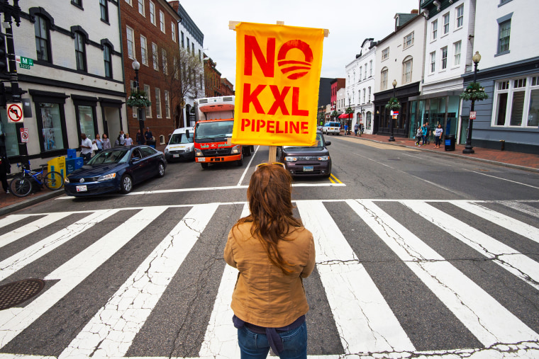 A protester holds an anti-Keystone XL sign at the intersection of Wisconsin and M Streets in Washington DC's Georgetown neighborhood, April 25, 2014.