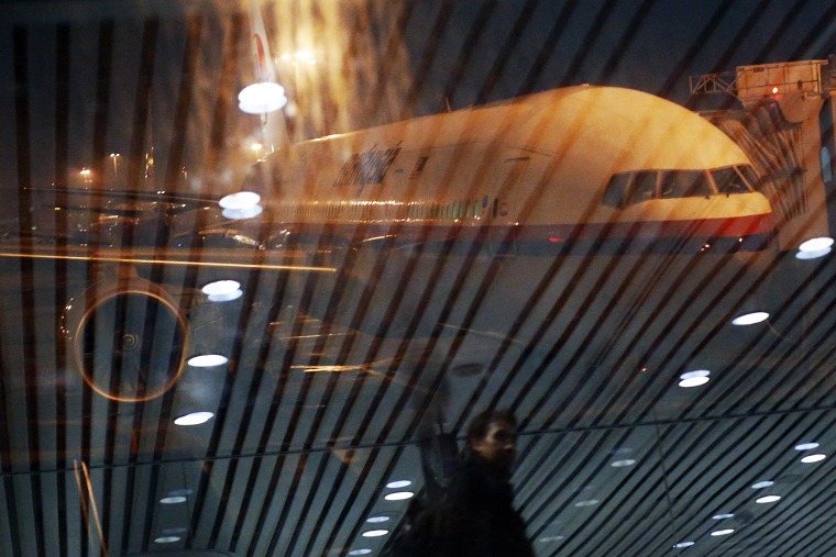 Malaysia Airlines Boeing 777-200ER flight MH318 to Beijing sits on the tarmac as passengers are reflected in the glass at the boarding gate at Kuala Lumpur International Airport, March 17, 2014.