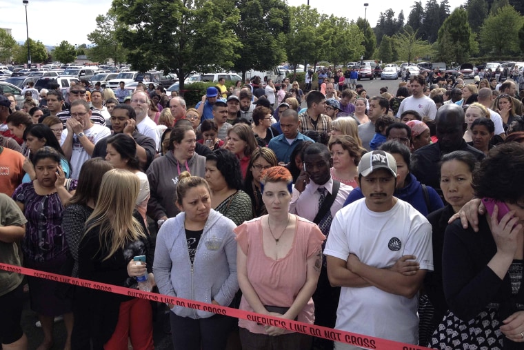 Parents wait behind police tape for students from Reynolds High School to arrive by bus in Troutdale, Oregon
