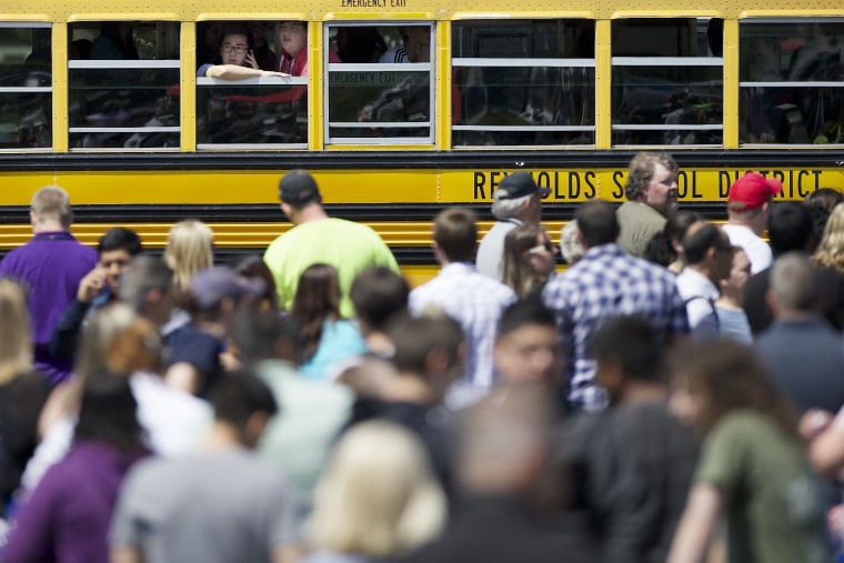 Students try to communicate and locate their family while waiting on a school bus as they arrived at a shopping center parking lot in Wood Village, Ore., after a shooting at Reynolds High School, June 10, 2014.