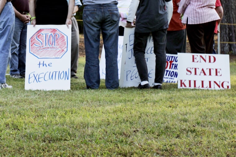 Protestors opposed to the death penalty hold signs and sing songs during a vigil at the Georgia Diagnostic and Classification Prison in Jackson, Georgia.