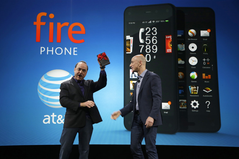 Ralph de la Vega, left, President and CEO of AT&T Mobility, accepts a gift from Amazon CEO Jeff Bezos, right, of what Bezos said is the first Amazon Fire Phone off the assembly line at the launch event for the new smartphone, Wednesday, June 18, 2014, in