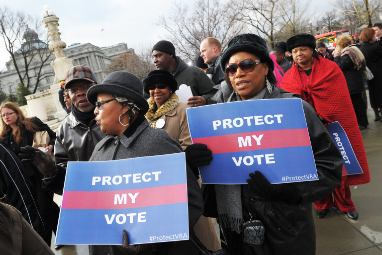 Activists hold a pro-voting rights placards outside of the US Supreme Court on February 27, 2013 in Washington, DC as the Court prepares to hear Shelby County vs Holder.